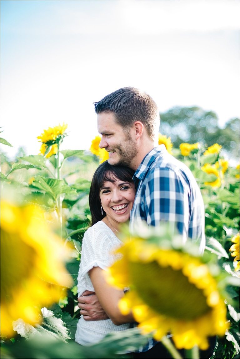 engagement picture of couple smiling naturally in sunflower field at sweetfields farm
