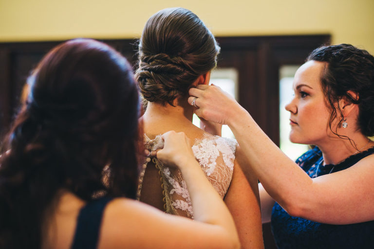 bridesmaids helping put on final touches to bride