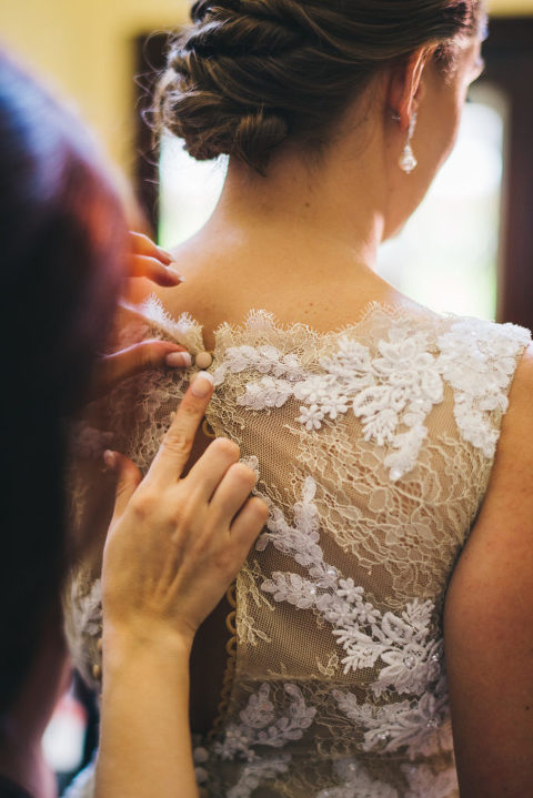 the last button of brides dress being put on