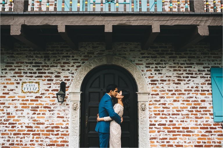 bride and groom kissing in front of casa feliz