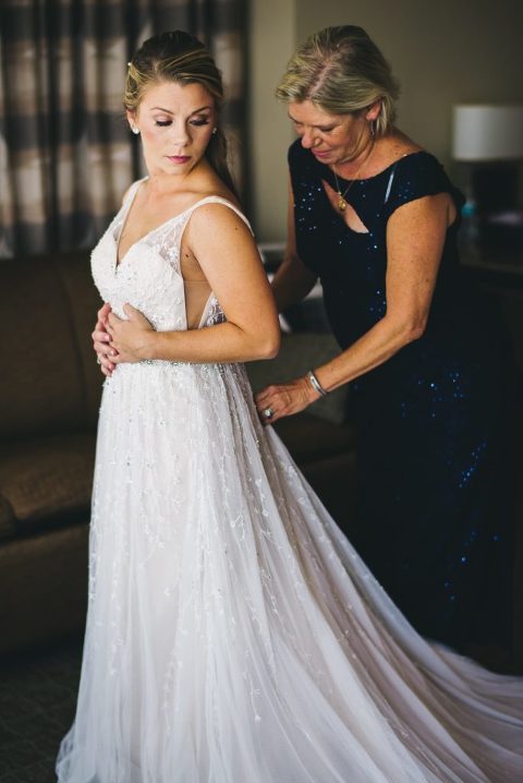mother of the bride helping bride put on dress