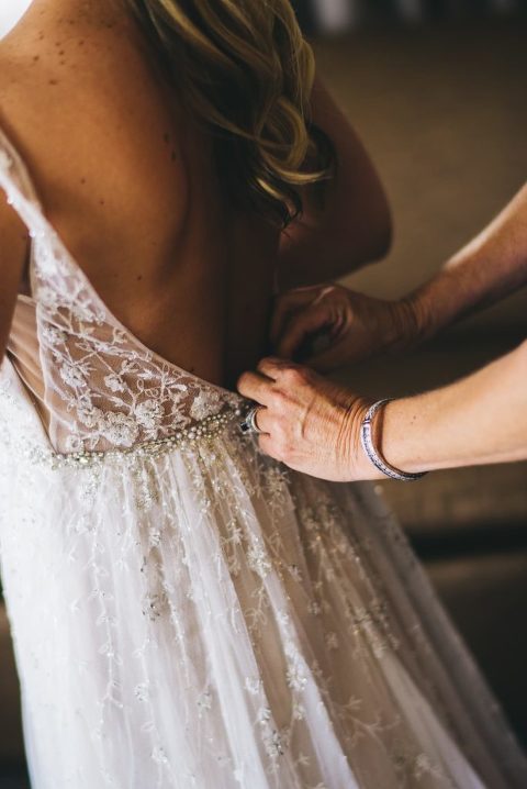 mother of the bride fastening buttons on wedding dress