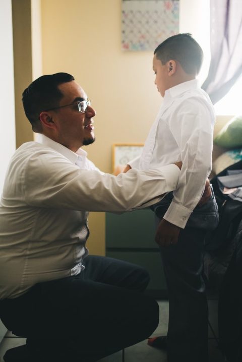 groom helping son get dressed