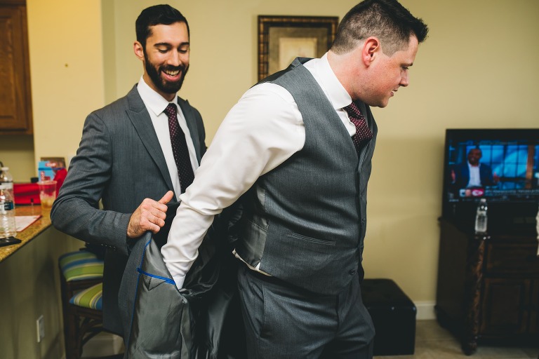 best man helping groom get dressed