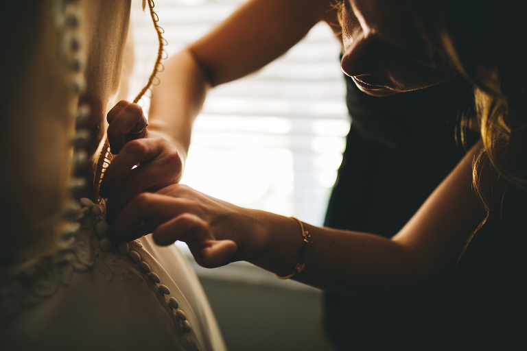 bride getting dress buttoned up